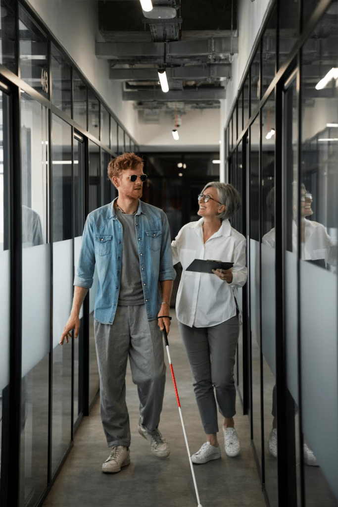 blind person walking in the office with a lady